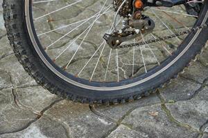 Bike wheel with pronounced tire tread and slightly rusty spokes. photo