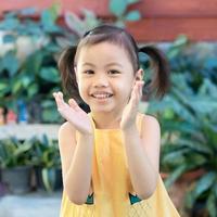 Positive charming 4 years old cute baby Asian girl, little preschooler child with adorable pigtails hair smiling looking at camera. photo