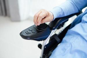 Asian elderly woman disability patient sitting on electric wheelchair in park, medical concept. photo