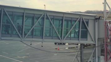 Passagiere verlassen das Flugzeug durch die Fluggastbrücke zum Flughafen video