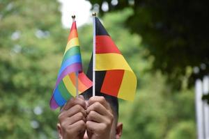 Rainbow flag and Germany national flag holding in hand, soft and selective focus, concept for celebration of lgbtq plus in pride month around the world. photo