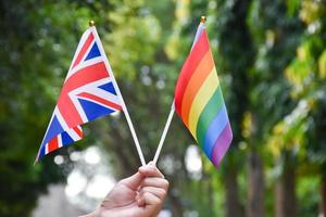 bandera del arco iris y bandera nacional de inglaterra o la bandera union jack sosteniendo en la mano, enfoque suave y selectivo, concepto para la celebración de lgbtq en el mes del orgullo en todo el mundo. foto