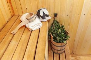 Interior details Finnish sauna steam room with traditional sauna accessories basin birch broom scoop felt hat towel. Traditional old Russian bathhouse SPA Concept. Relax country village bath concept. photo
