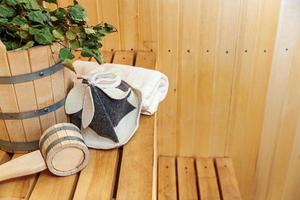 Interior details Finnish sauna steam room with traditional sauna accessories basin birch broom scoop felt hat towel. Traditional old Russian bathhouse SPA Concept. Relax country village bath concept. photo