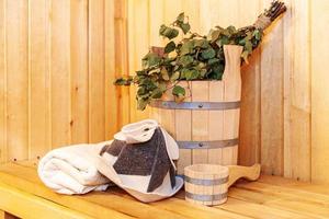 Interior details Finnish sauna steam room with traditional sauna accessories basin birch broom scoop felt hat towel. Traditional old Russian bathhouse SPA Concept. Relax country village bath concept. photo