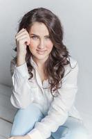 Girl in bright room sitting against white wall photo