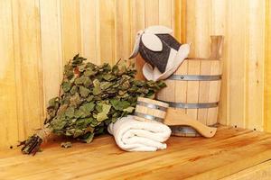 Interior details Finnish sauna steam room with traditional sauna accessories basin birch broom scoop felt hat towel. Traditional old Russian bathhouse SPA Concept. Relax country village bath concept. photo