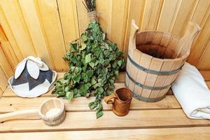 Interior details Finnish sauna steam room with traditional sauna accessories basin birch broom scoop felt hat towel. Traditional old Russian bathhouse SPA Concept. Relax country village bath concept. photo