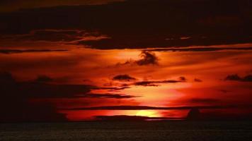 ciel brillant après le coucher du soleil, ciel rouge à l'horizon, nuages sombres glissent. long shot de la tombée de la nuit sur une île tropicale, vue sur la baie de la mer video