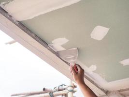 The ceiling worker is plastering the ceiling joints with high quality white gypsum plaster to keep the joints together. photo