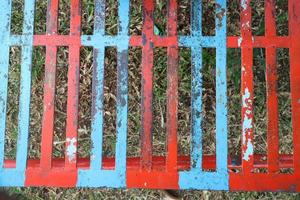 iron trellis with red and blue paint that has peeled off photo