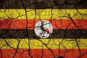 Dry soil pattern on the flag of Uganda. Country with drought concept. Water problem. Dry cracked earth country. photo