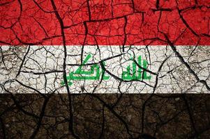 Dry soil pattern on the flag of Iraq. Country with drought concept. Water problem. Dry cracked earth country. photo