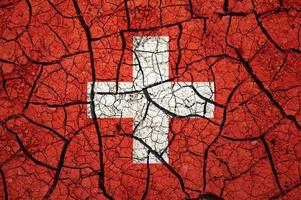 Dry soil pattern on the flag of Switzerland. Country with drought concept. Water problem. Dry cracked earth country. photo