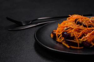 Korean salad with eggplant, carrots, garlic, spices and herbs on a dark concrete background photo