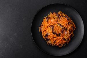 ensalada coreana con berenjena, zanahorias, ajo, especias y hierbas sobre un fondo de hormigón oscuro foto