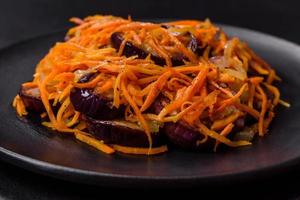 Korean salad with eggplant, carrots, garlic, spices and herbs on a dark concrete background photo