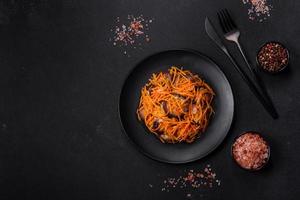 Korean salad with eggplant, carrots, garlic, spices and herbs on a dark concrete background photo