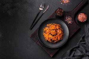 ensalada coreana con berenjena, zanahorias, ajo, especias y hierbas sobre un fondo de hormigón oscuro foto