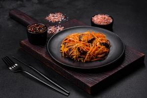 Korean salad with eggplant, carrots, garlic, spices and herbs on a dark concrete background photo