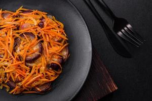 Korean salad with eggplant, carrots, garlic, spices and herbs on a dark concrete background photo