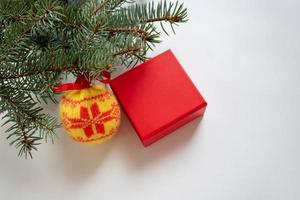 Natural fir branches with toys and a red gift box on a white background. Place for your text photo