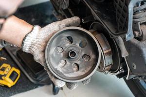 mechanic check auto Transmission system or Rear Clutch Pulley of  scooter Motorcycles in garage. maintenance, repair motorcycle concept in garage .selective focus photo