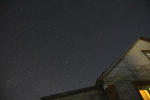 el cielo estrellado y los techos de las casas. astrofotografía en un pueblo con casas. foto