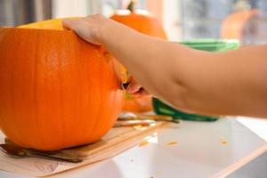 Woman cutting out pumpkin for a Halloween lantern photo