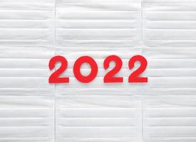 Red felt new year numbers 2022 on white medical masks background. Place for your text here. Review of the year results. photo