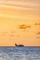 02.02.22, Ari atoll Exotic scene seaplane on Maldives sea landing. Seaplane landing on sunset sea. Vacation or holiday in Maldives background. Air transportation, Landing seaplane on the dawn seashore photo