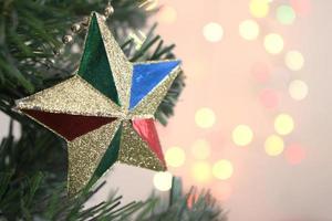 árbol de navidad con adornos estrella dorada con fondo bokeh claro foto