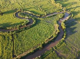 los arroyos serpentean en las zonas agrícolas durante la temporada de lluvias con abundante agua. verde y cálido en el sol de la mañana. foto