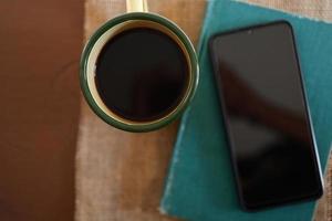 Yellow coffee mugs, phones and books on the wooden table inside the house. photo