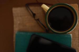 tazas de café amarillas, teléfonos y libros sobre la mesa de madera dentro de la casa. foto