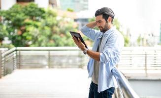 The young man using a tablet to working at out of office. The man wearing casual cloth and feeling thinking and seriously. photo