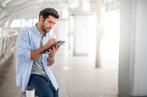 The young man using a tablet to working at out of office. The man wearing casual cloth and feeling thinking and seriously. photo