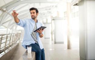 The young man using a tablet to working at out of office. The man wearing casual cloth and feeling relaxing and happy. photo