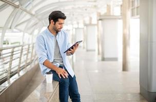 The young man using a tablet to working at out of office. The man wearing casual cloth and feeling relaxing and happy. photo