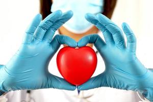 young female doctor holding a red heart standing on a white background photo