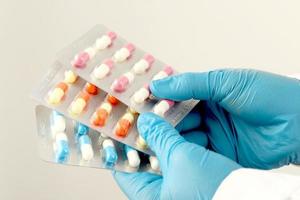The pharmacist or doctor holds the antibiotic capsules and gives them to the patient or person. overuse of antibiotics antimicrobial resistance white background photo