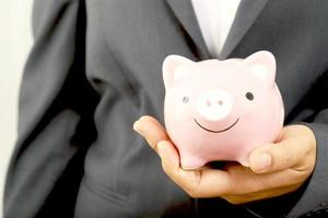 A businessman who has savings with a piggy bank photo