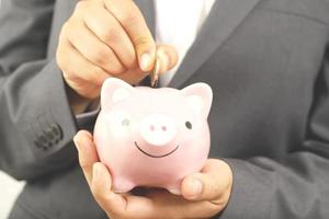 A businessman who has savings with a piggy bank photo