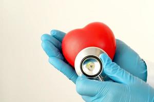 joven doctora sosteniendo un corazón rojo sobre un fondo blanco foto