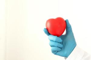 young female doctor holding a red heart standing on a white background photo