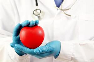 young female doctor holding a red heart standing on a white background photo