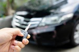 A woman holds a car key in front of a car in a showroom. photo