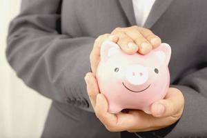 A businessman who has savings with a piggy bank photo