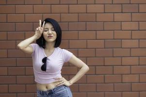 retrato de una chica hipster en el fondo de la pared de ladrillo, hermosa mujer asiática posa para tomar una foto