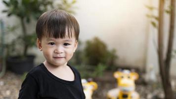 primer plano lindo niño asiático sonriendo feliz al aire libre. cara de bebé, niños felices jugando por la mañana. expresión confiada. la cara del niño muestra confianza. foto